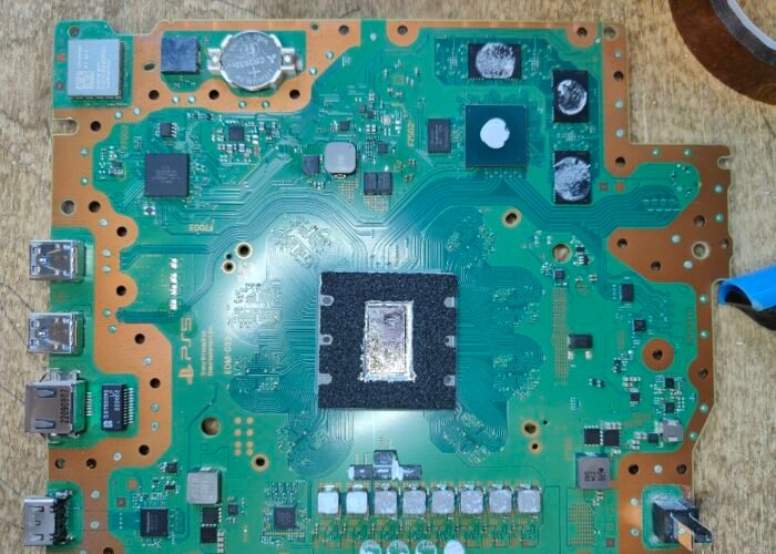 A PS5 motherboard showing the liquid metal as we found it on the APU. Coverage is very poor in one area and the thermal connection has deformed. We often see this in our Sheffield workshop on older consoles and ones that have stood vertically, where the liquid metal runs downwards. We cleaned the chip before applying new liquid metal.